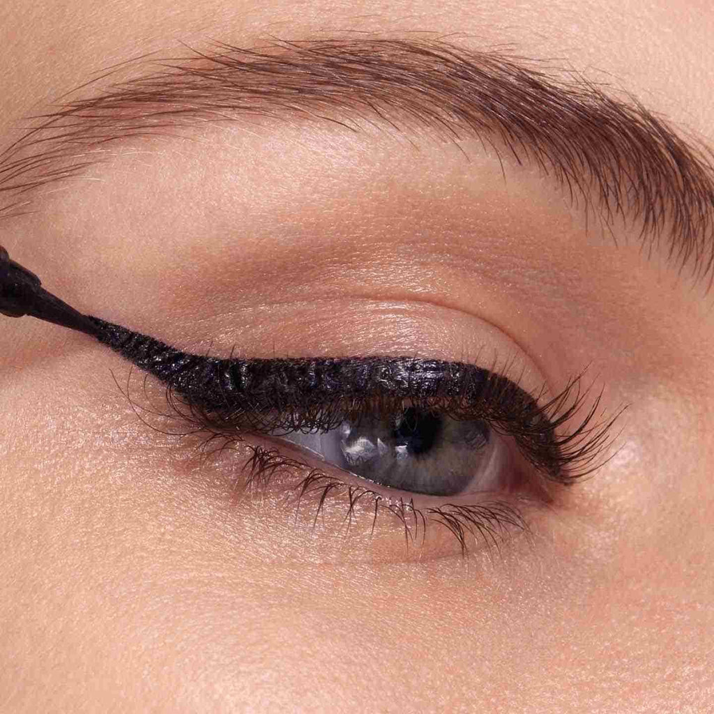Liquid eyeliner wing being extended up and out to create a winged eyeliner look.